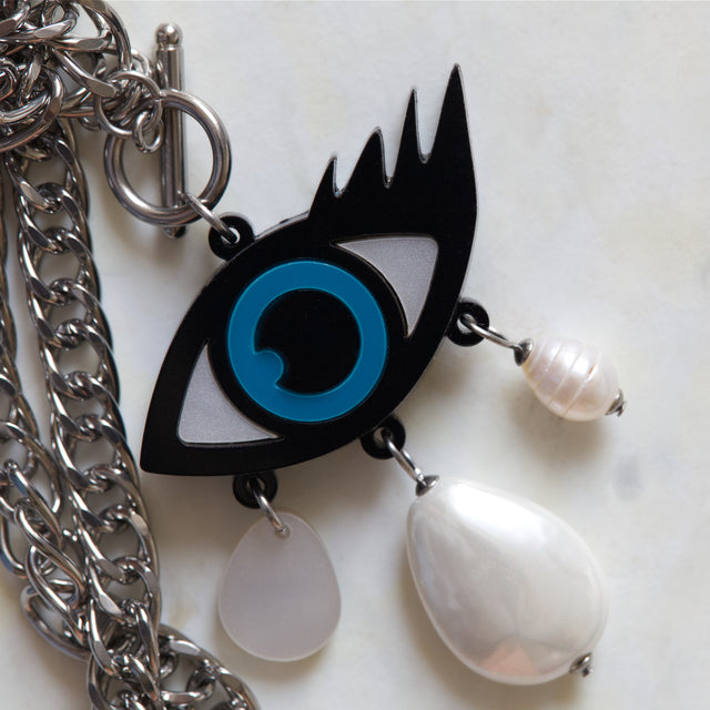 Gros plan sur le pendentif mauvais œil en acrylique noir, bleu et blanc avec perles