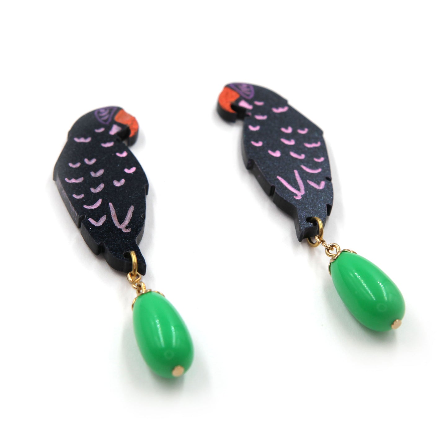 colose up side view of laser cut parrot statement earrings, hand painted with  green vintage beads on a white background