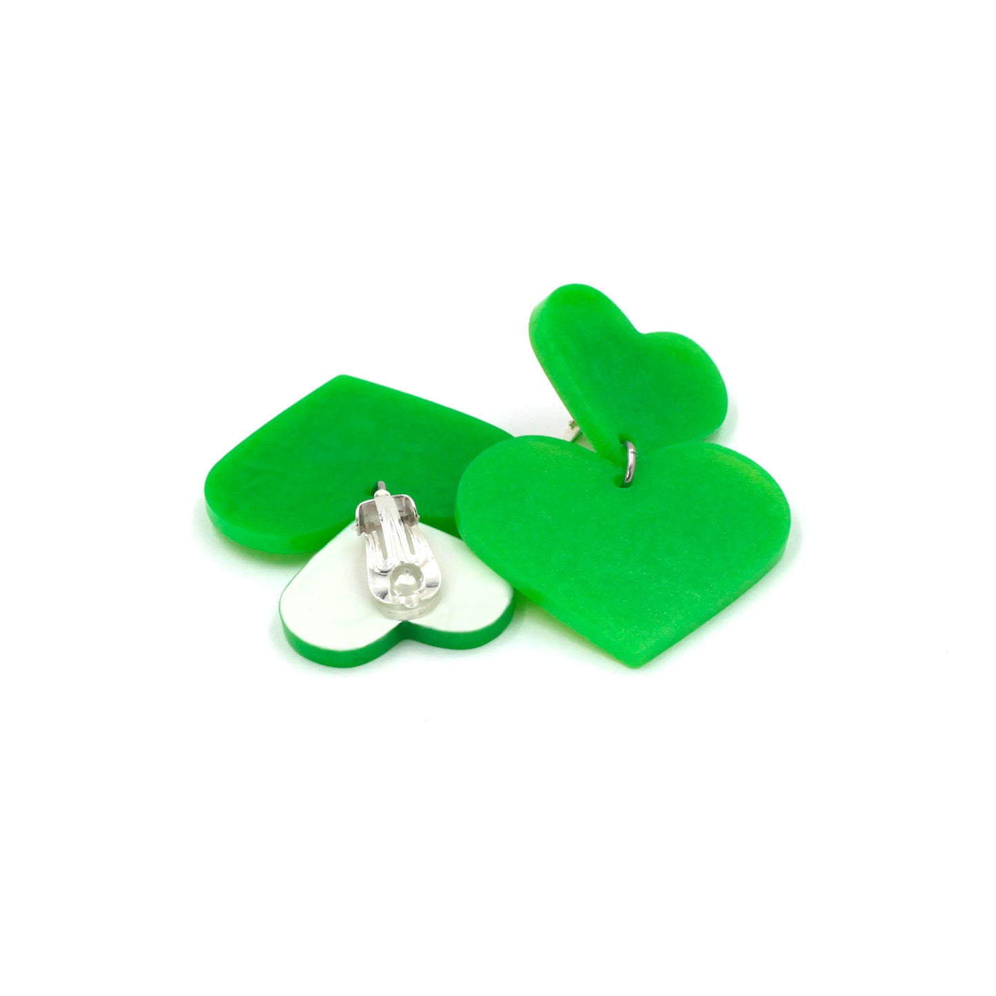 lime green hearts earrings on a white background. one is on its back, there is a clip on earring with a silicone pad protection. the top of the earring is white, the pendant heart is the same lime green from the front.