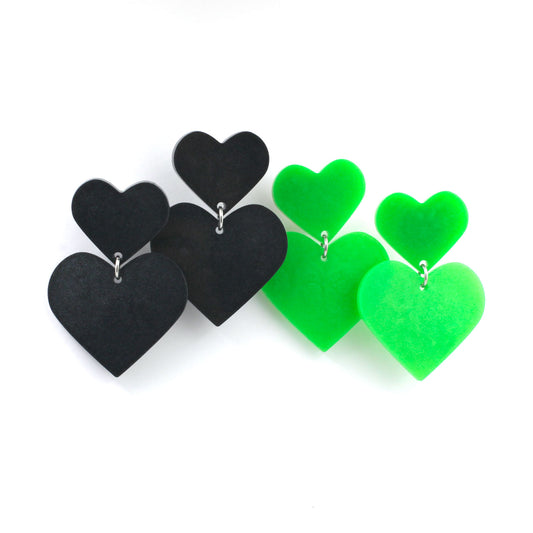 two pairs of hearts earrings on a white background. The earrings on the left are black and the one and the right are green. 