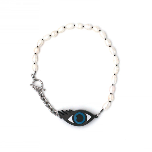 black laser cut acrylic eye with blue iris and black pupil with a chunky chain and freshwater pearls choker necklace on a white background