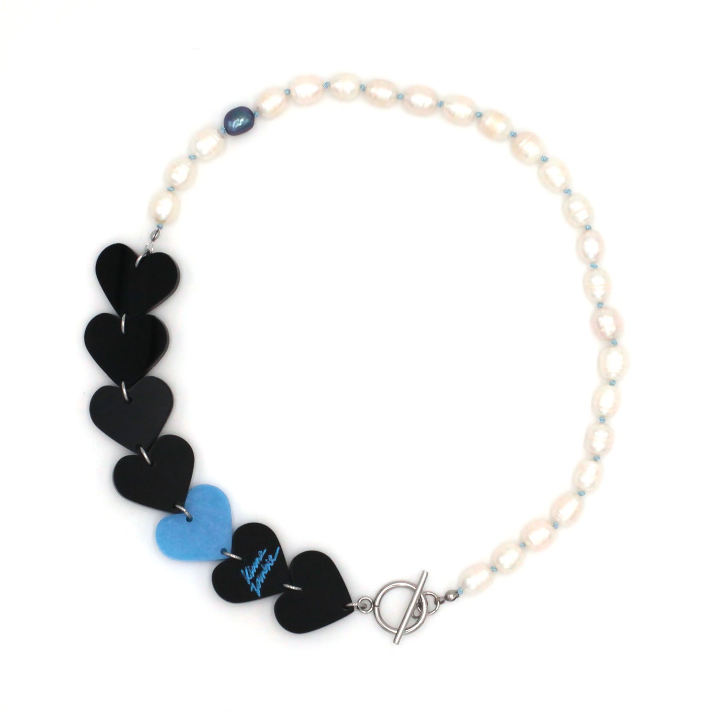 Laser-cut and resin black and blue hearts necklace with freshwater pearls and toggle clasp on a white background. 