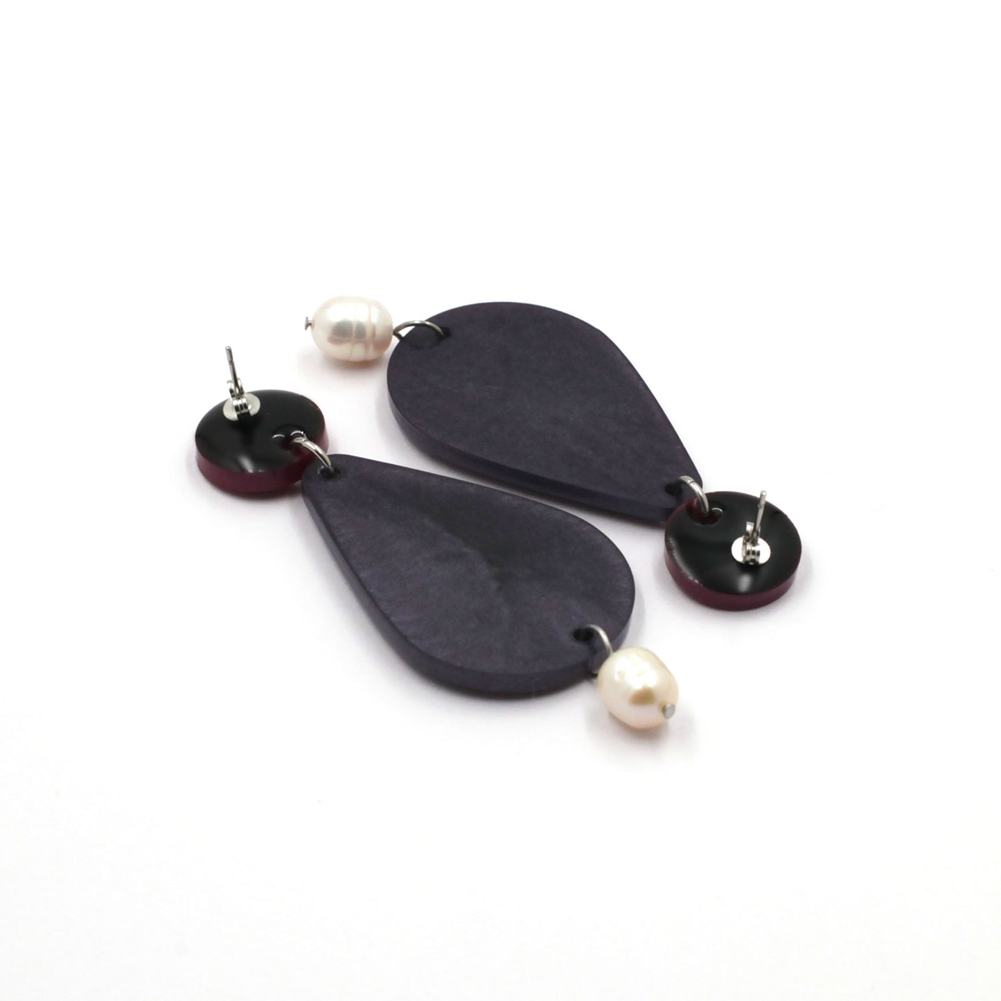 back of stud earrings composed by freshwater pearls, purple pear and a dot on a white background