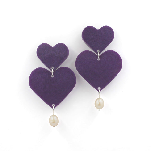 This is a picture of purple hearts earrings with freshwater pearls on a white background. 