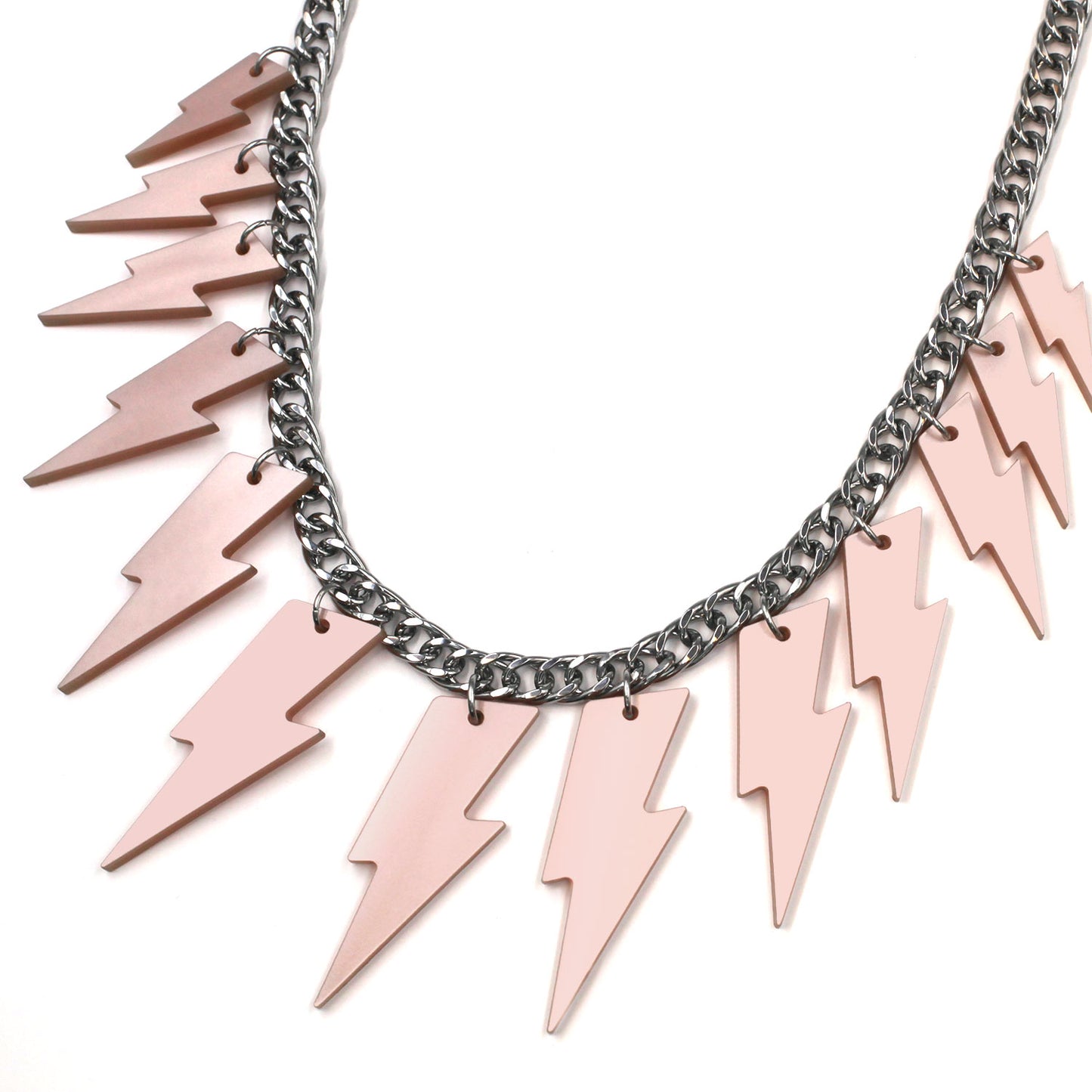 This is closeup of a necklace composed of a chunky silver tone curb chain with 13 pieces of pink pearly lightning bolts of graduant size on a white background.