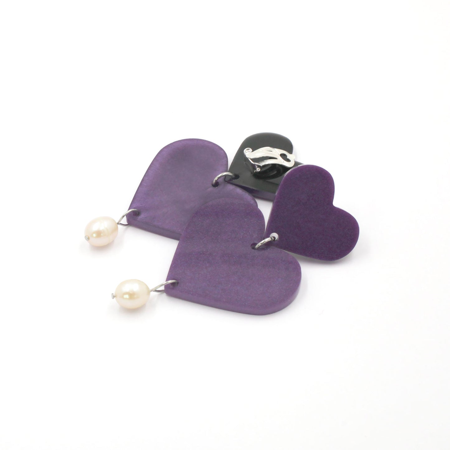This is a picture of purple hearts earrings with freshwater pearls on a white background.  one is on the back, the clip on are silver with silicone pad protection. 