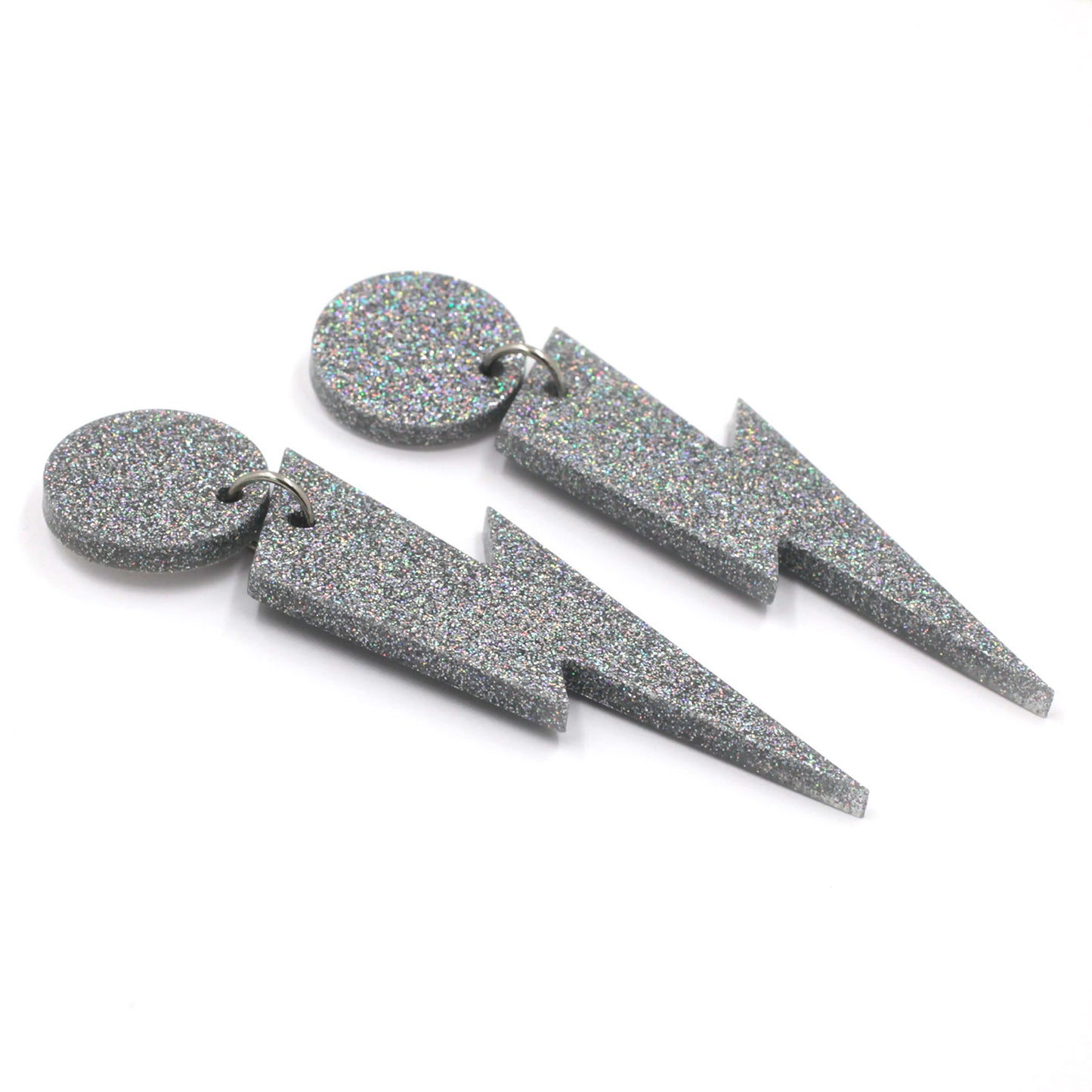 this is a picture of silver holographic glitter bolt and dot dangle earrings on a white background. 
