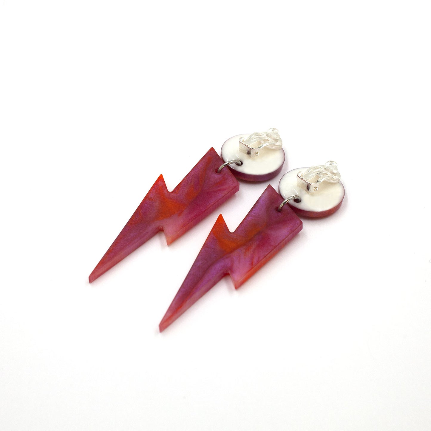 this is a picture of pink and orange marbled bolt and dot dangle earrings on a white background. one is on the back, the clip on are silver on a white dot.