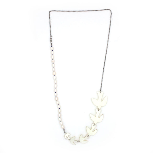 A long necklace is hanging from a white background, composed of pearls hand knotted silk thread, 6 birds large to small size and a thin silver tone chain.